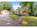 Charming yellow home featuring a detached garage, blooming hydrangeas, and inviting front porch at 310 S Spencer Ave, Spencer, NC 28159