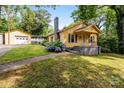Charming yellow home featuring a detached garage, blooming hydrangeas, and inviting front porch at 310 S Spencer Ave, Spencer, NC 28159