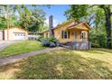 Charming yellow home featuring a detached garage, blooming hydrangeas, and inviting front porch at 310 S Spencer Ave, Spencer, NC 28159