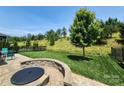 This backyard features a lush lawn, a stone fire pit, and privacy fencing, creating an inviting outdoor space at 5003 Looking Glass Trl, Denver, NC 28037