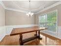 Bright dining room featuring hardwood floors, a modern chandelier, and a large window overlooking the yard at 6619 Hermsley Rd, Charlotte, NC 28278