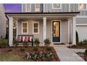 Inviting front porch with white columns, bench seating and a dark blue front door at 7101 Short Stirrup Ln, Mint Hill, NC 28227