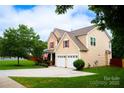 Well-maintained home with a lush green lawn and a spacious driveway leading to a two-car garage at 9805 Coatbridge Dr, Charlotte, NC 28269