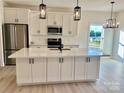 Bright open kitchen with white cabinets, stainless steel appliances, island with quartz countertops, and modern pendant lights at 120 Autumn Blaze Rd, China Grove, NC 28023