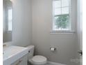 Clean half bathroom featuring a white vanity, modern toilet, and a bright window at 1211 Gold Rush Ct, Fort Mill, SC 29708