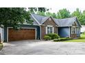Side view of a home featuring a brick and siding exterior, showcasing a spacious driveway and attached garage at 1305 Creekview Dr, Gastonia, NC 28052