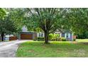 Inviting home exterior featuring a well-manicured lawn, mature trees, and a charming facade with a brick and siding combination at 1305 Creekview Dr, Gastonia, NC 28052