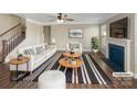 Bright living room features a ceiling fan, fireplace, large picture window, and contemporary furniture set with striped accents at 163 W Heart Pine Ln, Statesville, NC 28677