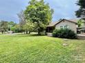 Charming single-story home with a lush green lawn and mature trees, featuring a covered porch and a carport at 1733 S Nc 16 Business Hwy, Stanley, NC 28164
