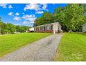 Quaint single-story home with a long driveway and well-maintained lawn, set against a backdrop of mature trees at 1812 Alpine Dr, Kings Mountain, NC 28086