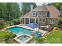 Aerial view of backyard with a swimming pool, hot tub, outdoor kitchen, patio, and lush landscaping at 3327 Lakeside Dr, Charlotte, NC 28270