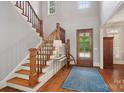 Bright foyer with hardwood floors, staircase, natural wood door and blue patterned rug at 3327 Lakeside Dr, Charlotte, NC 28270