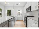 Modern kitchen featuring stainless steel appliances, an island, white cabinets and herringbone backsplash at 3920 Hager Dr, Charlotte, NC 28208