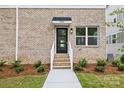 Close-up of a brick entryway with a black door and manicured landscaping at 3928 Hager Dr, Charlotte, NC 28208