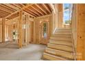 Unfinished entryway featuring a wooden front door and staircase, framed by exposed studs and beams at 4918 Buckingham Dr, Charlotte, NC 28209