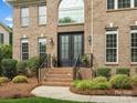 Inviting brick home featuring a grand entryway with black double doors and lush landscaping at 8921 Whittingham Dr, Waxhaw, NC 28173