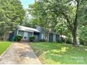 View of the home's exterior with a lovely front yard featuring a mature tree and lush landscaping at 11421 Kingfisher Dr, Charlotte, NC 28226