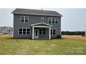 Back exterior showcasing a covered porch and a well-maintained lawn and an open field behind the property at 119 Tonbridge Way # Haf0033, Mooresville, NC 28115