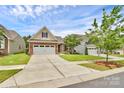 Exterior showcasing a well-manicured lawn, long driveway, and charming architecture with a mix of siding and brick elements at 12014 Belmont Mansion Dr, Charlotte, NC 28273