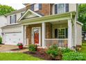 A welcoming brick front porch features a garden, white railings, and an inviting red front door at 1206 Craig Ave, Lancaster, SC 29720