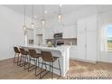 Bright, modern kitchen features white cabinetry, an island with barstool seating, and pendant lighting at 21011 Timber Tide Aly # 184, Lancaster, SC 29720