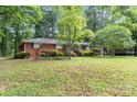 Traditional brick home with lush green lawn, mature trees providing shade, and an attached garage at 215 Jan Mar Dr, China Grove, NC 28023