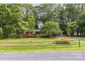 Traditional brick home with green trim surrounded by mature trees and a classic wooden fence at 215 Jan Mar Dr, China Grove, NC 28023