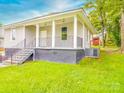Exterior view of a charming home with a covered porch, black railings, and well-kept landscaping at 2440 Myers St, Gastonia, NC 28056