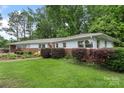 Charming single-story home with a brick accent wall and a well-manicured green lawn surrounded by lush trees at 2666 Providence Dr, Gastonia, NC 28052
