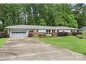 Single-story home with attached garage and well-manicured lawn, surrounded by lush trees in a peaceful setting at 2666 Providence Dr, Gastonia, NC 28052