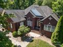 Aerial view of a brick home with a dark roof, surrounded by mature trees and landscaping at 3917 Erskine Woods Dr, Bessemer City, NC 28016
