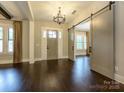 A spacious foyer with hardwood floors, a chandelier, and a sliding barn door at 9426 Greyson Ridge Dr, Charlotte, NC 28277