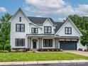 A beautiful two-story home with white siding, black trim, a gray garage door, and a well-manicured lawn at 9426 Greyson Ridge Dr, Charlotte, NC 28277