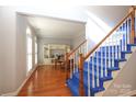 Bright entryway with hardwood floors, stairs with blue carpet, and a view to a cozy office at 9900 Colvard Cir, Charlotte, NC 28269