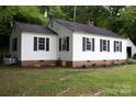 Side view of a single-story home with white siding, black shutters, brick foundation, and green lawn at 1250 Hampton Grace Ave, Lancaster, SC 29720