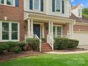 Inviting brick home showcasing a covered front porch with manicured landscaping at 2821 Providence Spring Ln, Charlotte, NC 28270