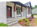 Inviting front porch featuring brick columns, new landscaping, and a craftsman-style front door at 501 Old Speedway Nw Dr # 1, Concord, NC 28027