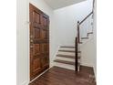 Entryway featuring a hardwood floor, staircase, dark door, and white walls at 6817 Dumbarton Dr, Charlotte, NC 28210