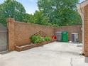 Enclosed brick patio with a brick planter bed, storage, and a grey concrete surface at 6817 Dumbarton Dr, Charlotte, NC 28210