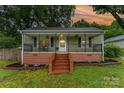 Charming single-story home featuring a welcoming front porch with decorative railings and manicured landscaping at 910 W A St, Kannapolis, NC 28081