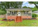 Charming single-story home featuring a welcoming front porch with decorative railings and manicured landscaping at 910 W A St, Kannapolis, NC 28081