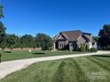 Wide front lawn and driveway leading to a home with stone and vinyl siding at 9125 Dylan Ridge Ct, Concord, NC 28027