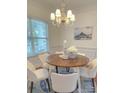 Bright dining area with a round wooden table, chandelier, and a picturesque window view at 1006 Phar Lap Dr, Indian Trail, NC 28079
