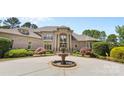 Elegant brick home featuring a grand entryway with a water fountain and lush, manicured landscaping at 1405 Saratoga Woods Dr, Waxhaw, NC 28173