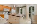 Well-lit kitchen with an island, white appliances, adjacent dining area, and a door leading to the outside at 159 Pitts School Nw Rd, Concord, NC 28027