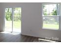Bright living room with wood floors, a sliding glass door to the yard, and a large window at 1922 Highland Park Dr, Charlotte, NC 28269
