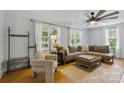 Bright living room featuring a large sofa, modern ceiling fan, and natural light from multiple windows at 4230 Train Chaser Pl, Indian Land, SC 29707