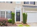 Close up of the front door with a decorative wreath, manicured landscaping, and an attached garage at 444 Battery Cir, Clover, SC 29710