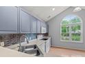 Bright kitchen featuring modern blue cabinets, a stylish backsplash, and a large window at 4557 Panther Pl, Charlotte, NC 28269