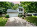 Two-story home with driveway, two-car garage, landscaped lawn and mature trees in a pleasant setting at 6033 Edinmeadow Ln, Charlotte, NC 28269